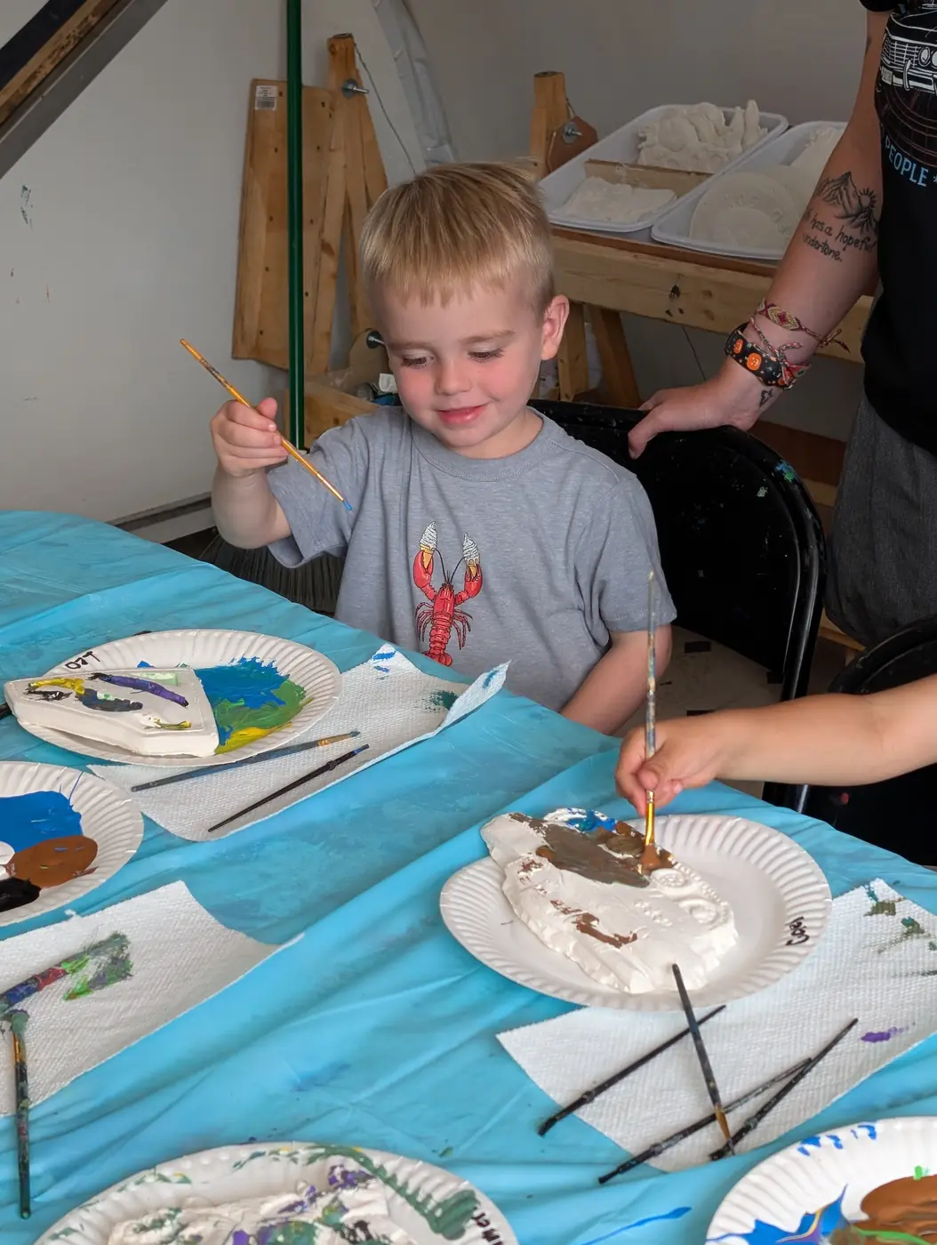 A preschooler painting a handmade clay project at Blossom Station