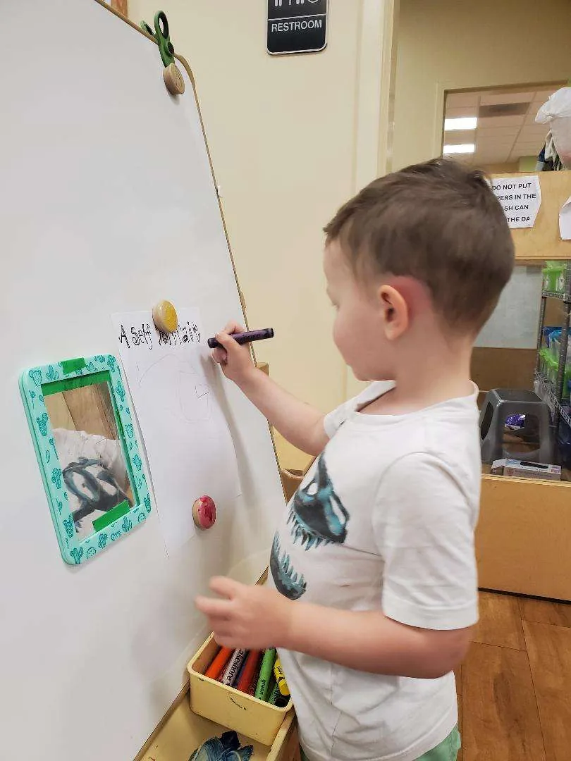 A preschooler drawing and writing at Blossom Station