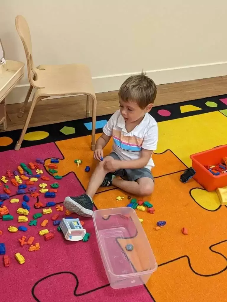 A child building and playing on the classroom activity rug at Blossom Station