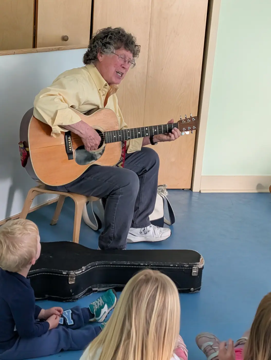 A musician playing guitar and singing with children during music enrichment at Blossom Station in Acton, MA