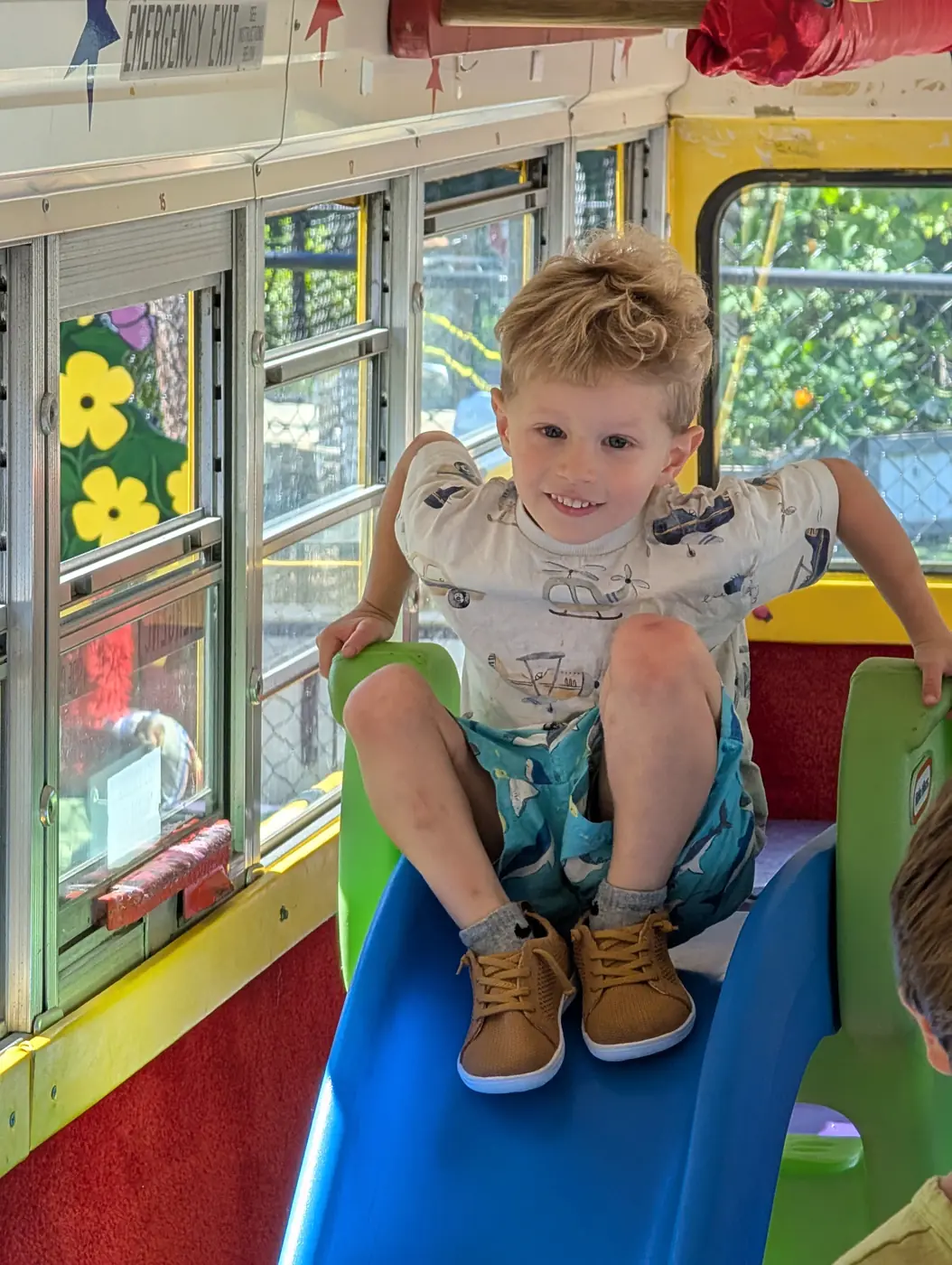 A smiling child on the indoor slide at Blossom Station in Acton, MA