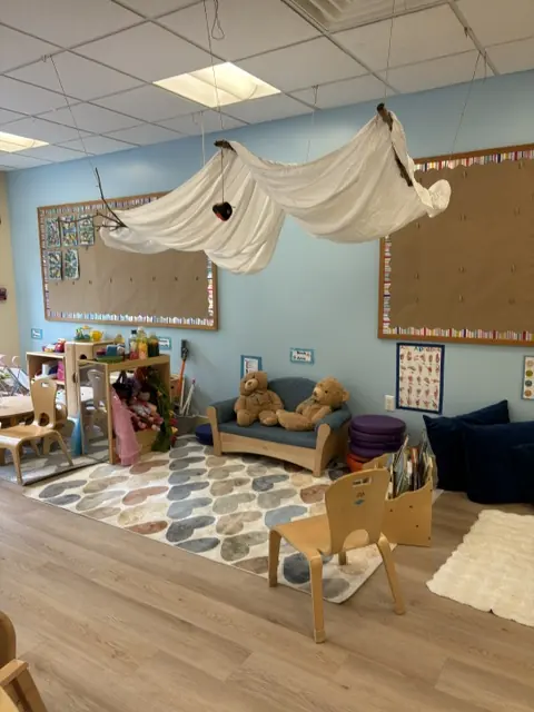 A cozy reading nook with a fabric canopy, soft seating, and books at Blossom Station in Acton, MA