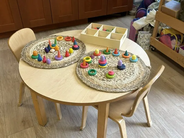 A fine-motor activity table with wooden loose parts and sorting rings at Blossom Station