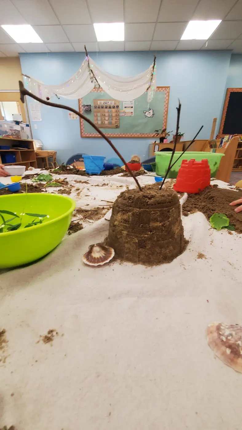 A sand castle decorated with shells at the summer under-the-sea sensory table at Blossom Station